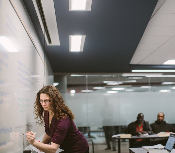 Female student writing on the whiteboard in a classroom at Cornerstone University's Professional & Graduate Studies