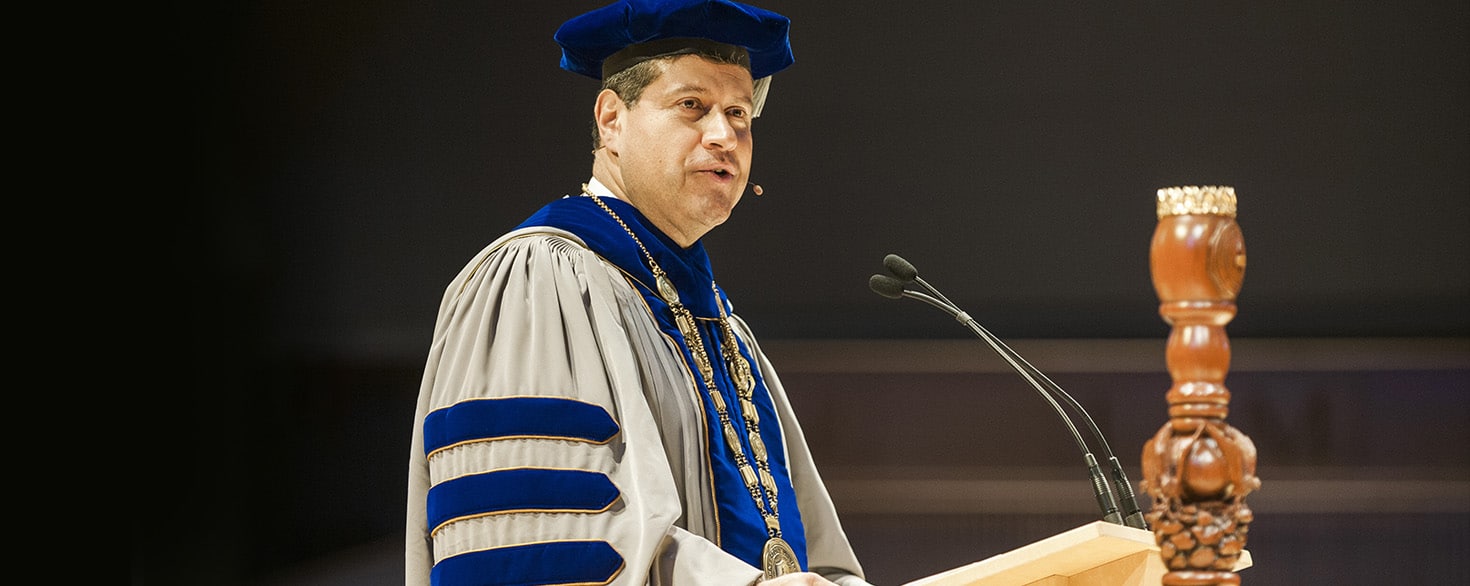 Gerson Moreno-Riaño speaking from a wooden podium on the stage of Christ Chapel at Cornerstone University