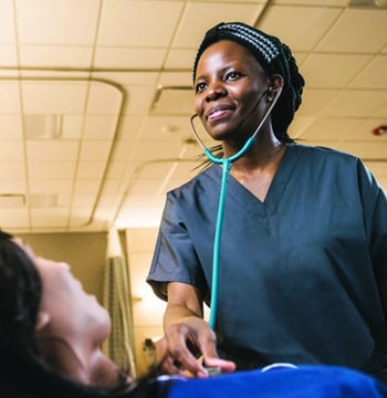 Female nursing student using a stethoscope on a mannequin