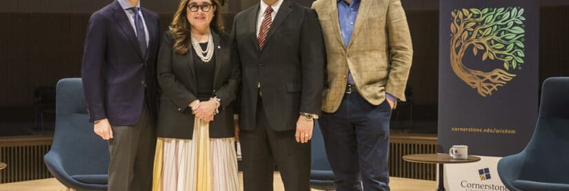 Noah Feldman, Mary Ann Gomez Orta, Gerson Moreno-Riaño and Ross Douthat standing on the stage in Christ Chapel at Cornerstone University near a banner that says Wisdom Conversations