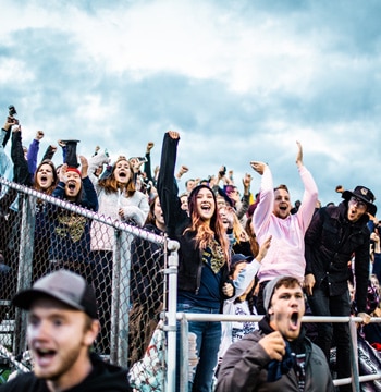 College students and fans standing and cheering in bleachers