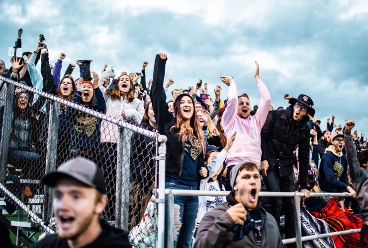 College students and fans standing and cheering in bleachers