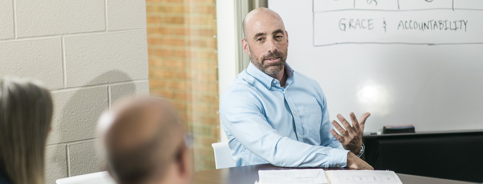 Male sitting at conference table in front of whiteboard
